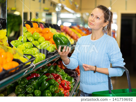 woman buy large pepper in supermarket woman buy large pepper in supermarket 141759692