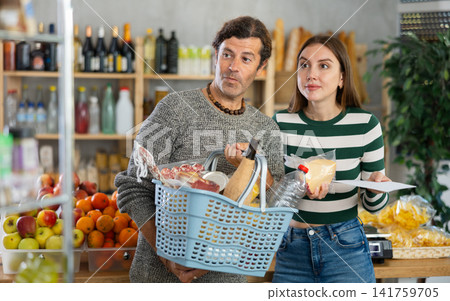 Enthusiastic couple shopping with list in grocery store Enthusiastic couple shopping with list in grocery store 141759705