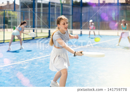 Athletic woman playing racket in paddle tennis weekend in parks Athletic woman playing racket in paddle tennis weekend in parks 141759778