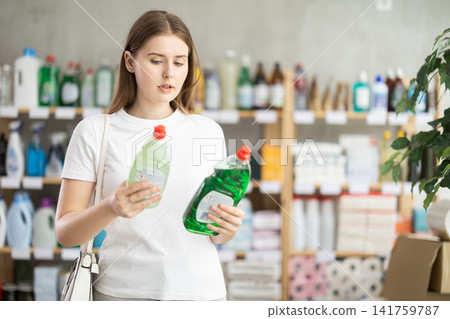 Young woman chooses dishwashing detergent in store Young woman chooses dishwashing detergent in store 141759787