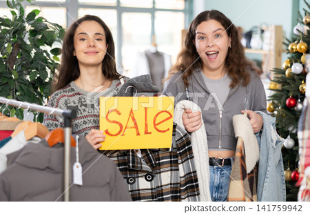 Two young women presents sale sign in store 141759942