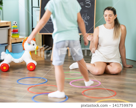 Boy performs exercises and steps into center of circle outlined by plastic ring Boy performs exercises and steps into center of circle outlined by plastic ring 141759979