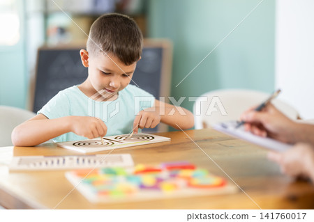 Child psychologist asks boy to play game: using both hands to simultaneously navigate maze drawn on board Child psychologist asks boy to play game: using both hands to simultaneously navigate maze drawn on board 141760017