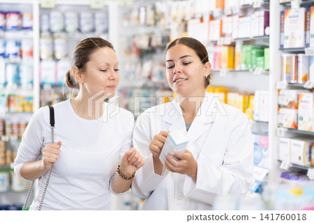 Woman pharmacist helping woman customer to choose remedy in pharmacy Woman pharmacist helping woman customer to choose remedy in pharmacy 141760018