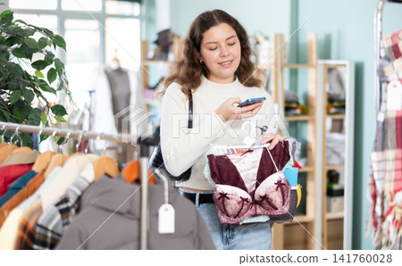 Young woman scans qr code of lingerie in store Young woman scans qr code of lingerie in store 141760028
