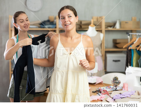 Female seamstress puts on jacket for girl client 141760031