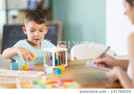 Boy plays with wooden sorter 141760050