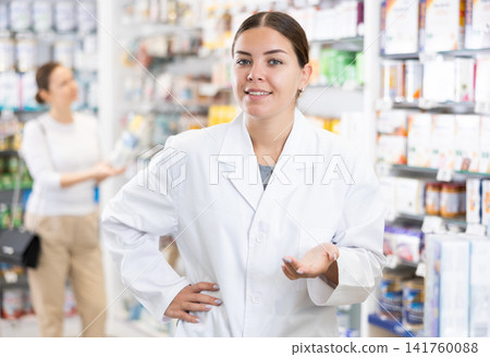 At pharmacy, apothecary waiting for customers and invites with gesture go to department of cosmetics At pharmacy, apothecary waiting for customers and invites with gesture go to department of cosmetics 141760088