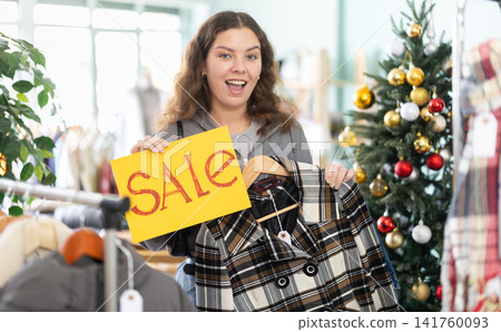 Girl with poster in hands announces X mas discounts Girl with poster in hands announces X mas discounts 141760093