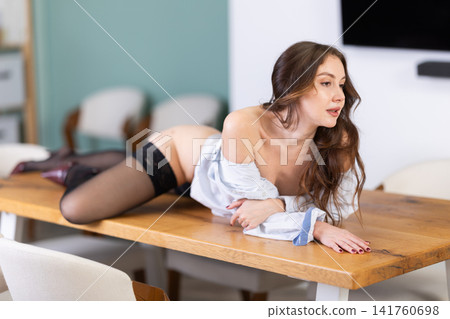 Brunette seductively lying in shirt in office Brunette seductively lying in shirt in office 141760698