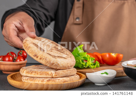 Chef Preparing Fresh Pita Bread with Mediterranean Ingredients Chef Preparing Fresh Pita Bread with Mediterranean Ingredients 141761148