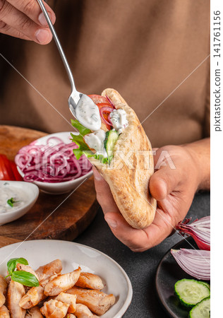 Chef Adding Yogurt Sauce to Chicken Pita Pocket Chef Adding Yogurt Sauce to Chicken Pita Pocket 141761156