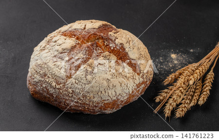 Artisan sourdough bread loaf with wheat ears on dark background Artisan sourdough bread loaf with wheat ears on dark background 141761223