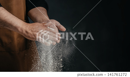 Baker clapping flour covered hands with flying flour particles Baker clapping flour covered hands with flying flour particles 141761272