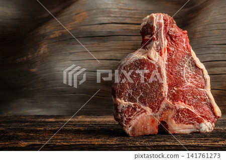 Raw bone in beef steak on rustic wooden background with copy space Raw bone in beef steak on rustic wooden background with copy space 141761273