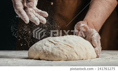 Baker dusting artisan bread dough with flour before baking 141761275