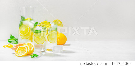 Refreshing homemade lemon water with mint and ice on white background with copy space Refreshing homemade lemon water with mint and ice on white background with copy space 141761363