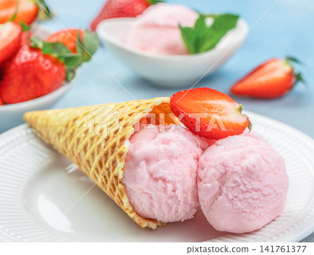 Strawberry ice cream scoops in waffle cone with fresh berries Strawberry ice cream scoops in waffle cone with fresh berries 141761377