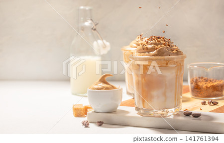 Whipped dalgona iced coffee with milk and coffee ingredients on bright background Whipped dalgona iced coffee with milk and coffee ingredients on bright background 141761394