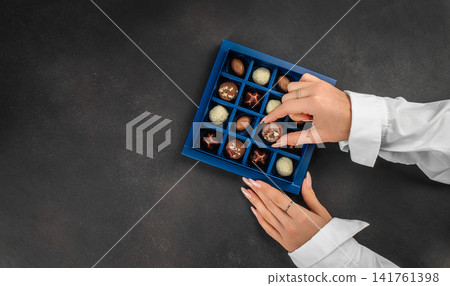 Woman selecting chocolate from luxury gift box 141761398