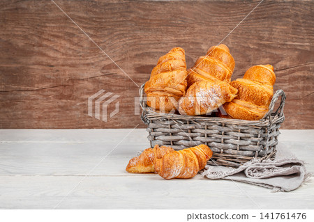 Fresh Croissants in Wicker Basket on Rustic Wooden Table with Copy Space Fresh Croissants in Wicker Basket on Rustic Wooden Table with Copy Space 141761476