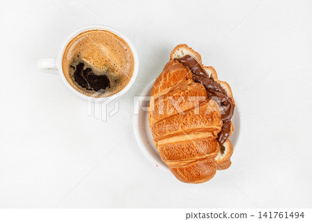 Chocolate croissant sandwich with coffee on white background top view Chocolate croissant sandwich with coffee on white background top view 141761494