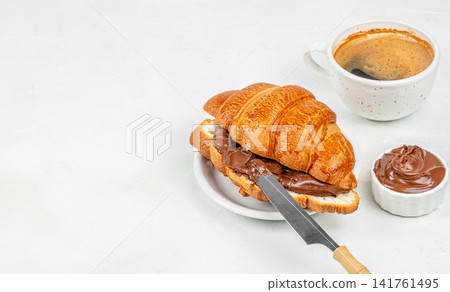 Chocolate Croissant Sandwich with Hazelnut Spread and Coffee on White Background Chocolate Croissant Sandwich with Hazelnut Spread and Coffee on White Background 141761495