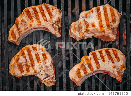 Grilled pork chops on barbecue grill with charcoal top view Grilled pork chops on barbecue grill with charcoal top view 141761550