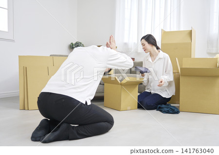 搬家時，一名男子深深鞠躬道歉，而一名女子正在收拾行李。 141763040