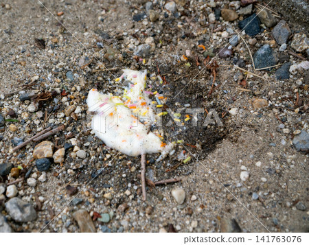 A photo capturing the scene of ice cream melting on sandy ground, with colorful spray paint scattered around. A photo capturing the scene of ice cream melting on sandy ground, with colorful spray paint scattered around. 141763076