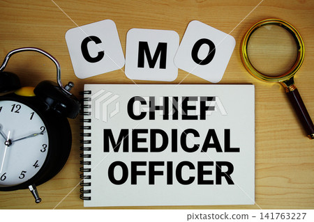 CMO Chief Medical Officer text written on notepad with magnifying glass and alarm clock on wooden background CMO Chief Medical Officer text written on notepad with magnifying glass and alarm clock on wooden background 141763227