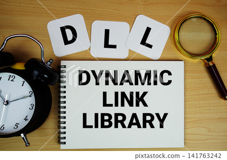 DLL Dynamic Link Library text written on notepad with magnifying glass and alarm clock on wooden background DLL Dynamic Link Library text written on notepad with magnifying glass and alarm clock on wooden background 141763242