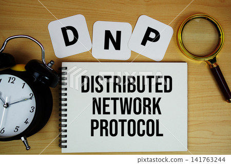 DNP Distributed Network Protocol text written on notepad with magnifying glass and alarm clock on wooden background DNP Distributed Network Protocol text written on notepad with magnifying glass and alarm clock on wooden background 141763244