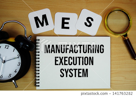 MES Manufacturing Execution System text written on notepad with magnifying glass and alarm clock on wooden background MES Manufacturing Execution System text written on notepad with magnifying glass and alarm clock on wooden background 141763282