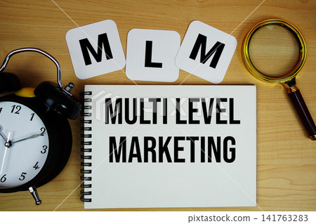 MLM Multi Level Marketing text written on notepad with magnifying glass and alarm clock on wooden background MLM Multi Level Marketing text written on notepad with magnifying glass and alarm clock on wooden background 141763283