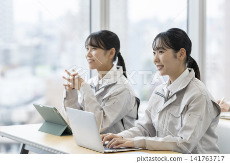 一名身穿工作服的年輕女子正在接受培訓 一名身穿工作服的年輕女子正在接受培訓 141763717