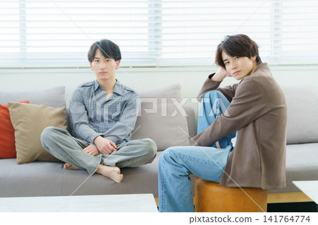 Portrait of two Gen Z men sitting on a sofa Portrait of two Gen Z men sitting on a sofa 141764774
