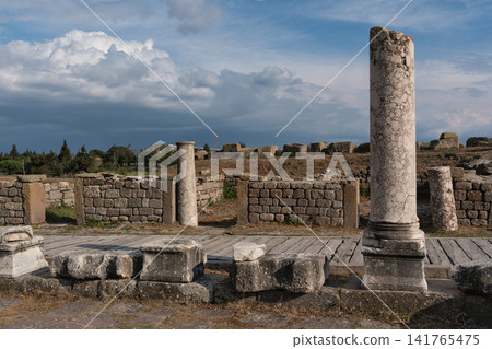 Ancient Pergamon ruins with weathered columns and stone walls against a cloudy sky, Bergama, Turkey Ancient Pergamon ruins with weathered columns and stone walls against a cloudy sky, Bergama, Turkey 141765475