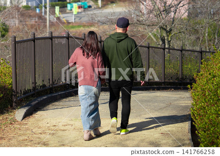 公園長廊上,一男一女並肩而行,背影清晰可見。 公園長廊上,一男一女並肩而行,背影清晰可見。 141766258