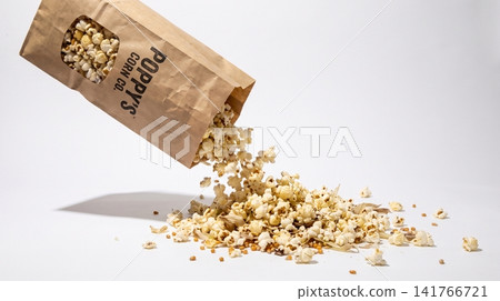 Brown paper bag spilling gourmet popcorn on white table with spilling seasoned snacking appetizer culinary delicious Brown paper bag spilling gourmet popcorn on white table with spilling seasoned snacking appetizer culinary delicious 141766721