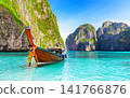 Traditional Thai longtail boat floating in the turquoise waters of Maya Bay on Phi Phi Islands, Thailand. One of the most iconic tropical travel destinations in Southeast Asia. 141766876