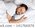 Close-up portrait of a relaxed man sleeping soundly on a soft pillow. Ideal concept for healthy lifestyle, sleep quality, stress relief and personal wellbeing. 141766878