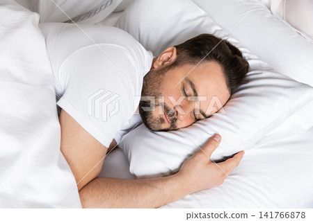 Close-up portrait of a relaxed man sleeping soundly on a soft pillow. Ideal concept for healthy lifestyle, sleep quality, stress relief and personal wellbeing. Close-up portrait of a relaxed man sleeping soundly on a soft pillow. Ideal concept for healthy lifestyle, sleep quality, stress relief and personal wellbeing. 141766878