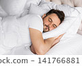 Young adult man sleeping comfortably, while resting on a soft pillow. Concept of healthy sleep, relaxation, wellness, recovery and everyday comfort. 141766881