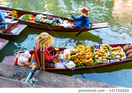 Traditional vendors selling fresh tropical fruit from wooden boats at the famous Damnoen Saduak Floating Market near Bangkok in Thailand. Traditional vendors selling fresh tropical fruit from wooden boats at the famous Damnoen Saduak Floating Market near Bangkok in Thailand. 141766889