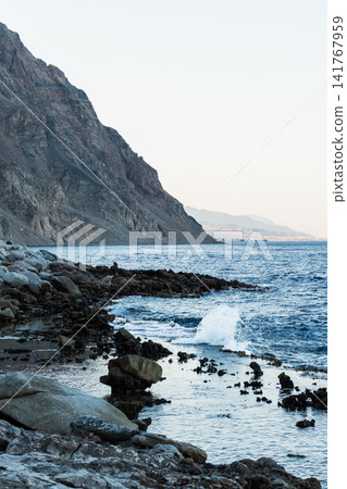 Natural pools with calm blue water along the Red Sea coast in Dahab, Egypt. Rocky shoreline under the Sinai mountains with clear blue water. Natural pools with calm blue water along the Red Sea coast in Dahab, Egypt. Rocky shoreline under the Sinai mountains with clear blue water. 141767959
