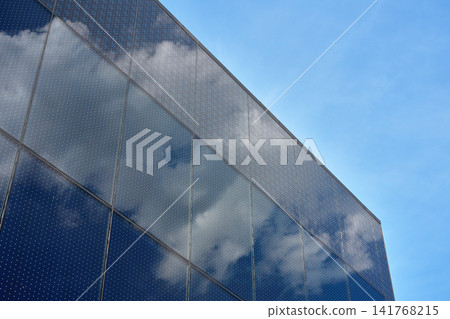Glass facade reflecting clouds on modern building Glass facade reflecting clouds on modern building 141768215