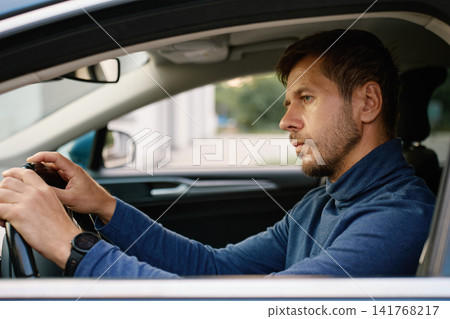 Focused man driving car and looking at road ahead 141768217