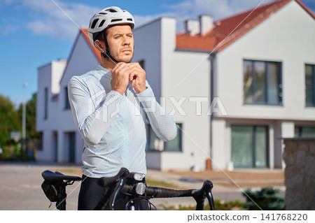 Cyclist fastening bicycle helmet strap before a ride Cyclist fastening bicycle helmet strap before a ride 141768220