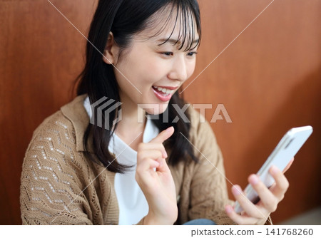 Image of a woman smiling while using a smartphone Image of a woman smiling while using a smartphone 141768260